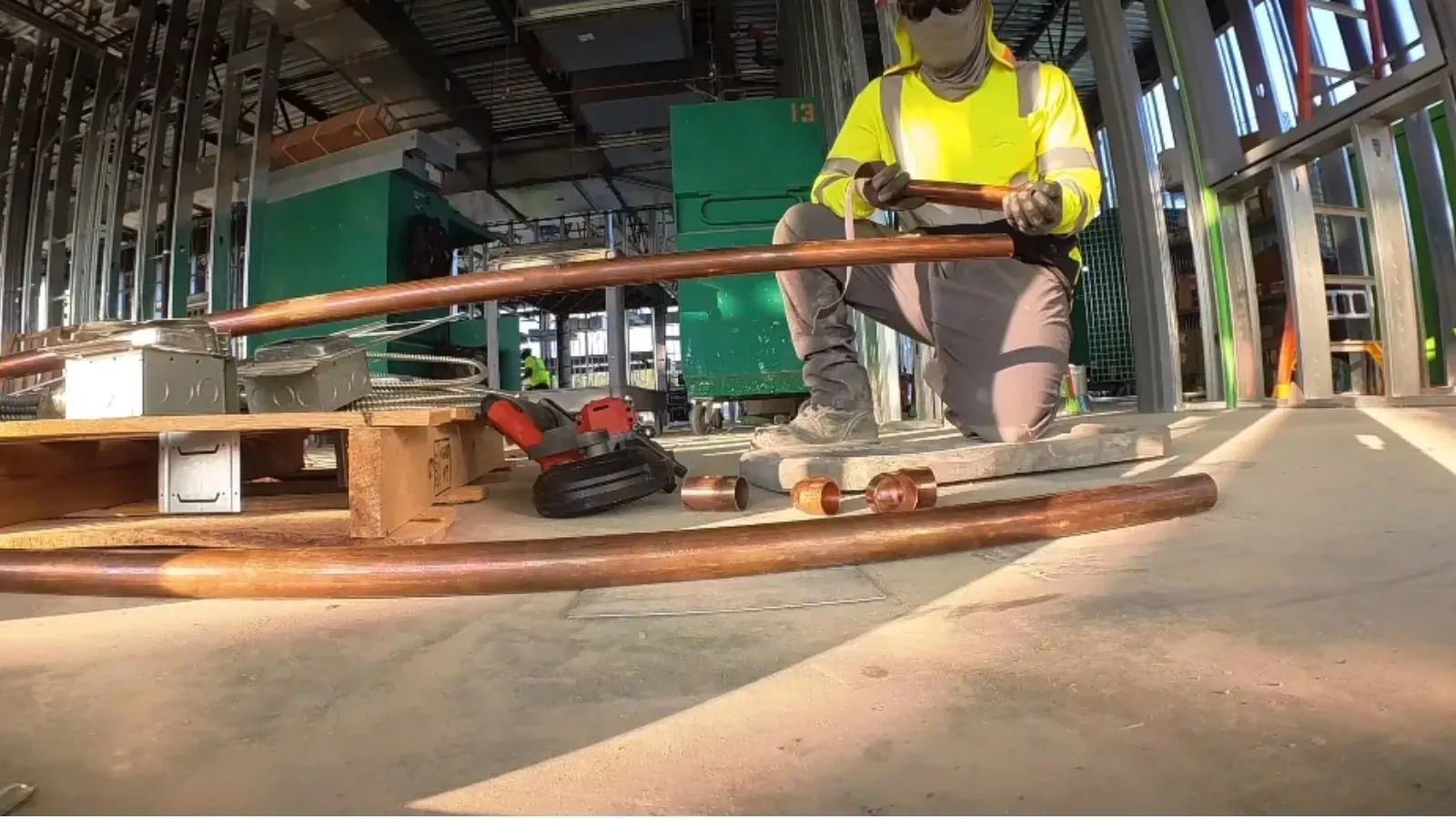 Plumber laying copper pipe on a construction site floor