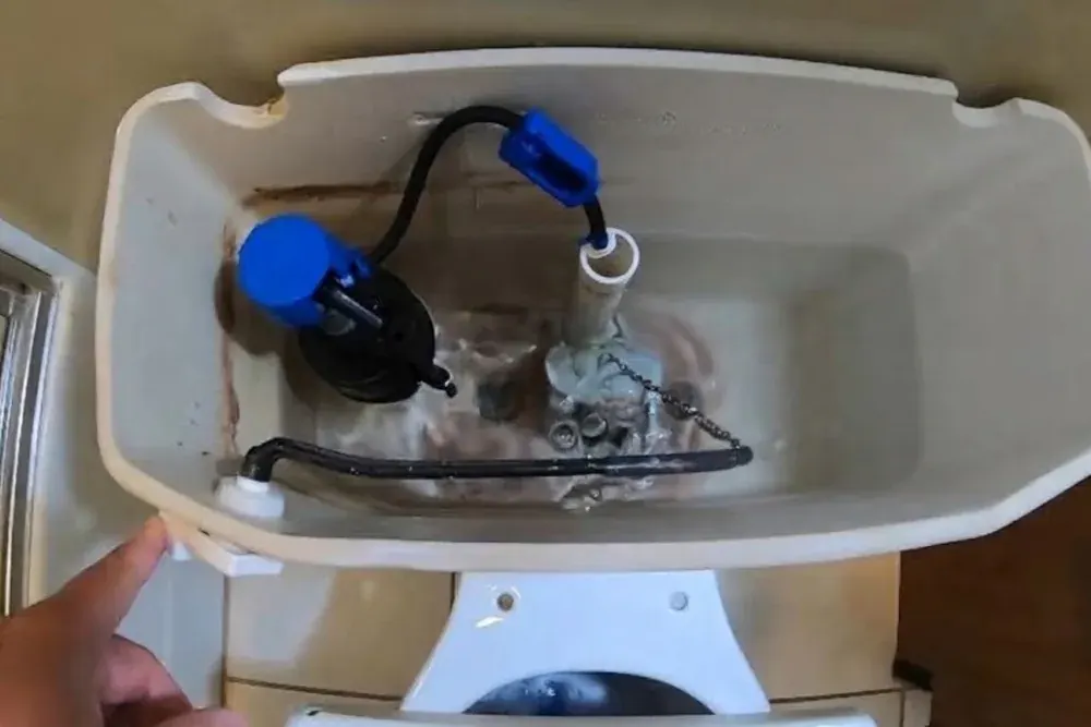 Open toilet tank showing the fill valve and flapper