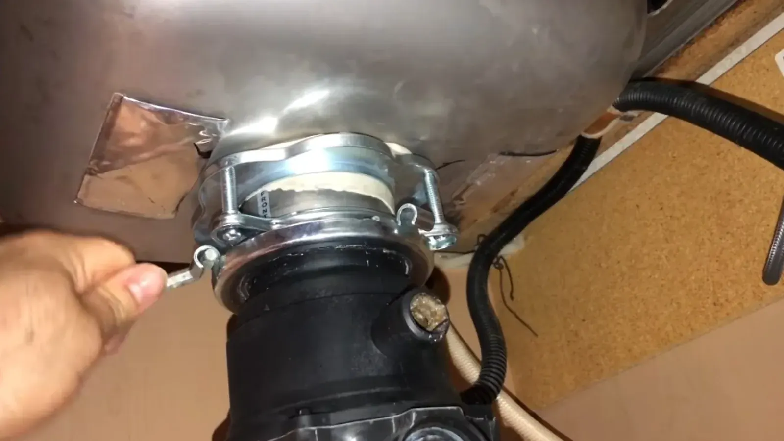 Hand tightening the mounting ring of a garbage disposal under a sink
