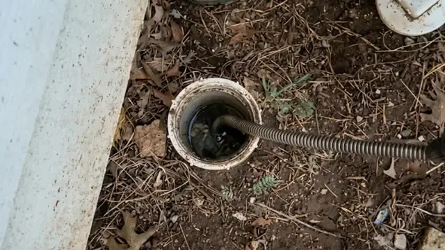 Drain cable entering an outdoor sewer cleanout in the ground