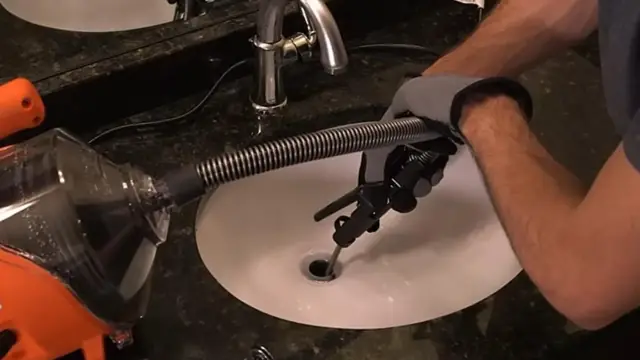 Plumber feeding a drain machine cable into a bathroom sink