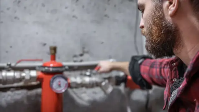 Plumber checking a pressure gauge and valve on a supply line
